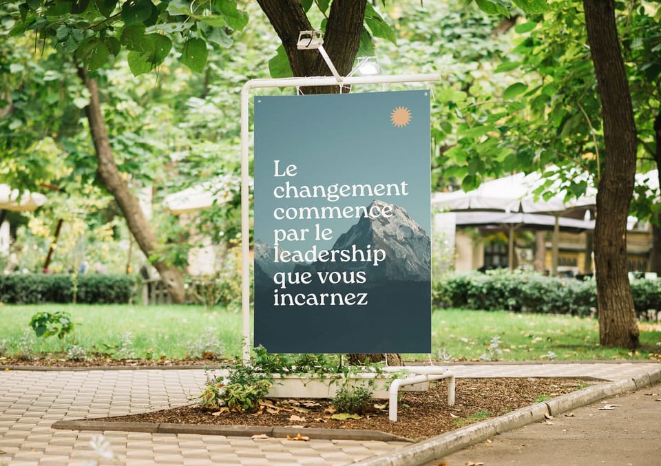 Panneau Innovative Sharing dans un parc avec la phrase Le changement commence par le leadership que vous incarnez